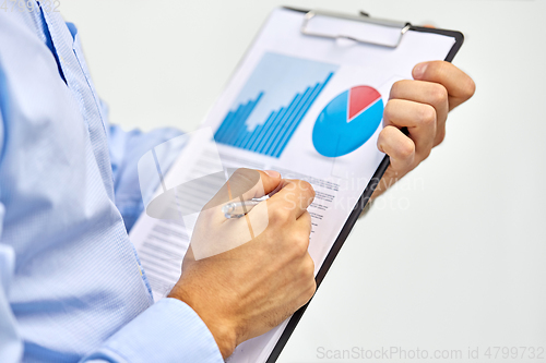 Image of hands of businessman holding clipboard with charts