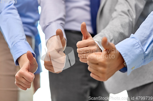 Image of close up of business team hands showing thumbs up