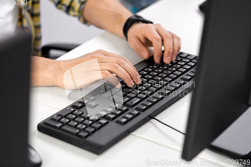 Image of male hands typing on computer keyboard on table