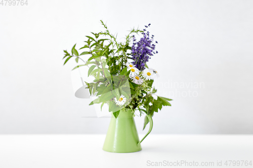 Image of bunch of herbs and flowers in green jug on table