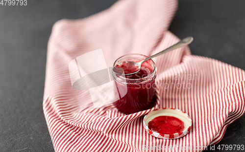 Image of mason jar with raspberry jam and spoon on towel