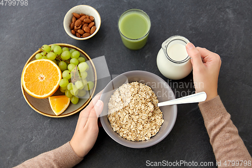 Image of hands with oatmeal, fruits, nuts, juice and milk