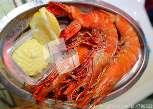 Image of Jumbo shrimps with lemon and sauce on metal plate
