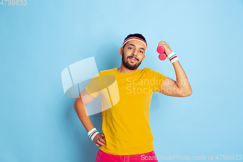 Image of Young caucasian man in bright clothes training on blue background