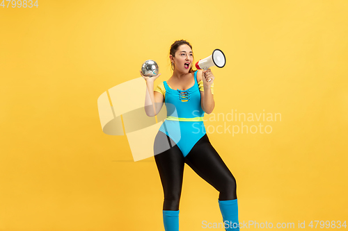 Image of Young caucasian plus size female model\'s training on yellow background