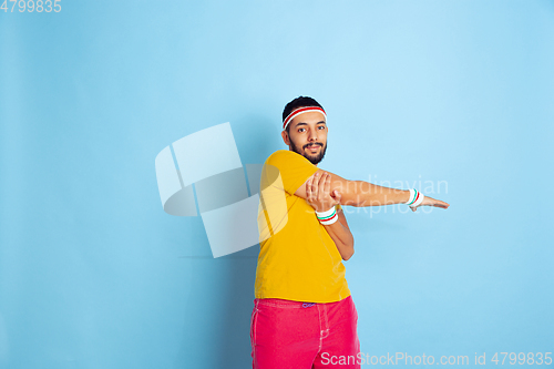 Image of Young caucasian man in bright clothes training on blue background