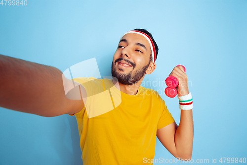 Image of Young caucasian man in bright clothes training on blue background