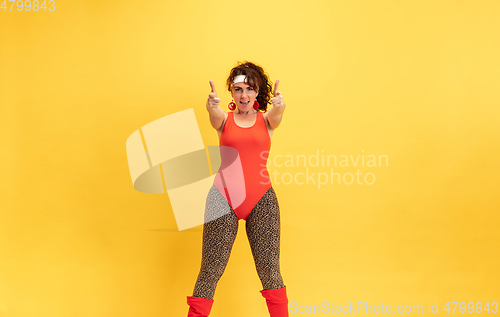 Image of Young caucasian plus size female model\'s training on yellow background