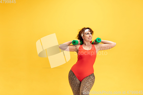 Image of Young caucasian plus size female model\'s training on yellow background