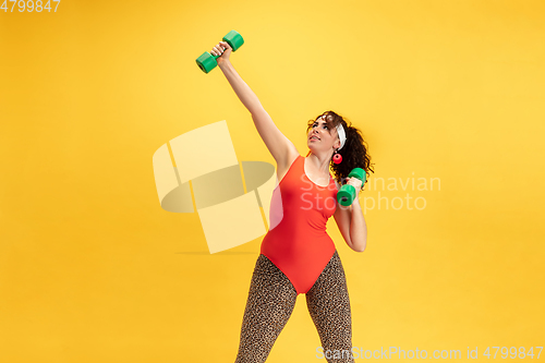 Image of Young caucasian plus size female model\'s training on yellow background