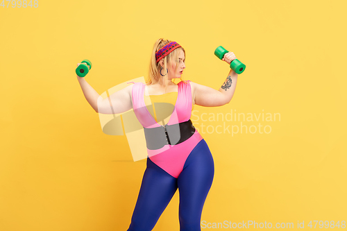 Image of Young caucasian plus size female model\'s training on yellow background