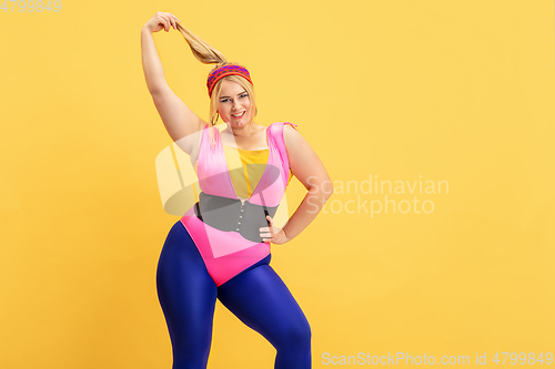 Image of Young caucasian plus size female model\'s training on yellow background