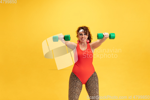 Image of Young caucasian plus size female model\'s training on yellow background