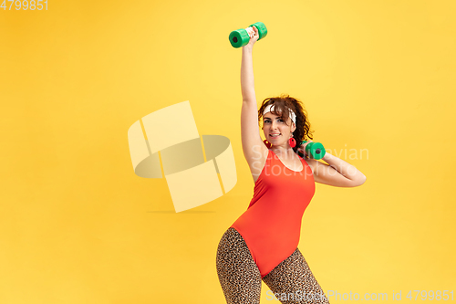 Image of Young caucasian plus size female model\'s training on yellow background