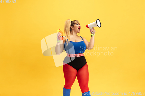 Image of Young caucasian plus size female model\'s training on yellow background