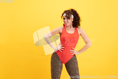 Image of Young caucasian plus size female model\'s training on yellow background