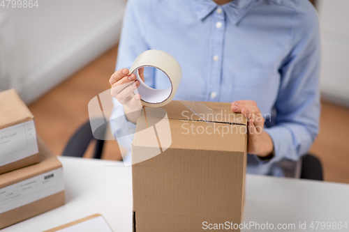 Image of woman packing parcel box with adhesive tape