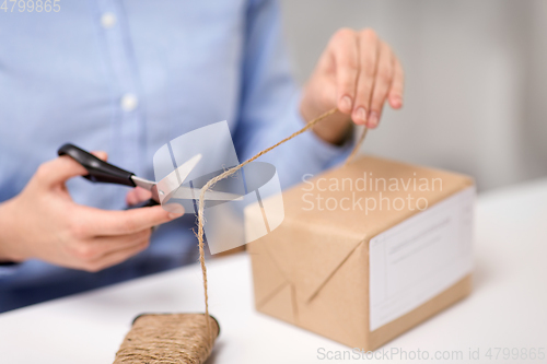 Image of woman with parcel cutting rope at post office