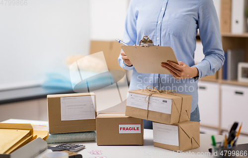 Image of woman with parcels and clipboard at post office