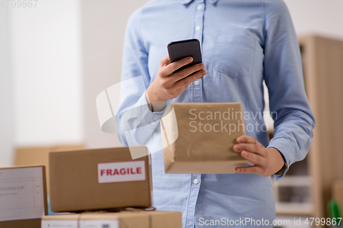 Image of woman with smartphone and parcels at post office