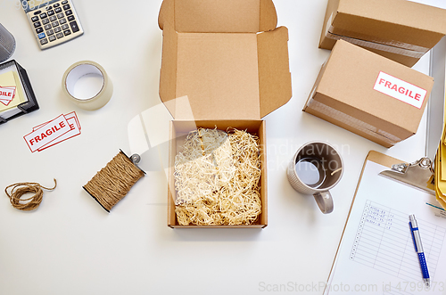 Image of parcel with straw filler and mug at post office