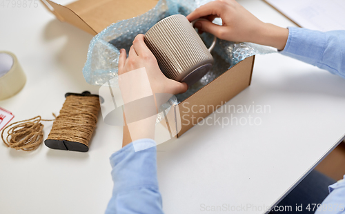 Image of hands packing mug to parcel box at post office