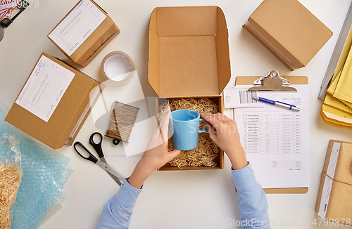 Image of hands packing mug to parcel box at post office