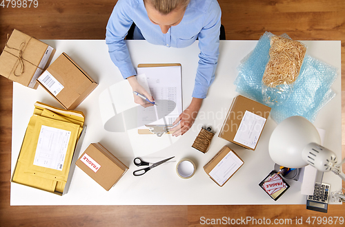 Image of woman with clipboard and parcels at post office