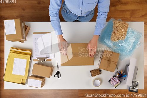 Image of woman packing parcel box with adhesive tape