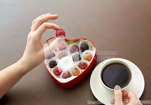 Image of hands, candies in heart shaped box and coffee cup