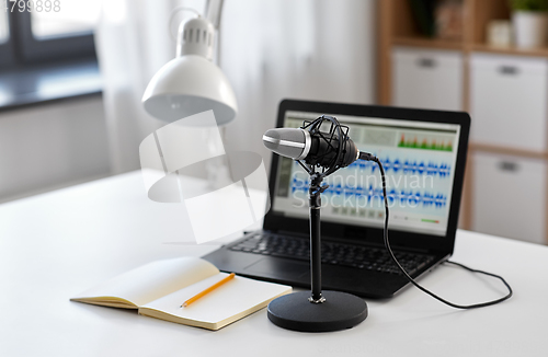 Image of microphone, laptop and notebook on table