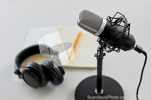 Image of headphones, microphone and notebook with pencil