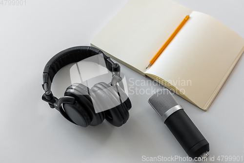 Image of headphones, microphone and notebook with pencil