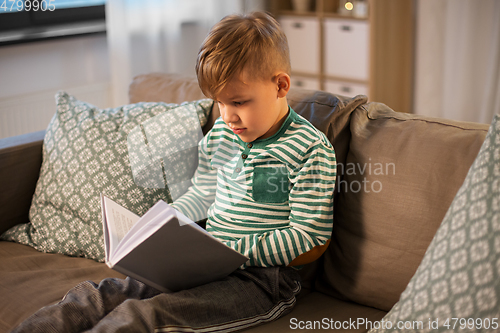 Image of little boy reading book at home