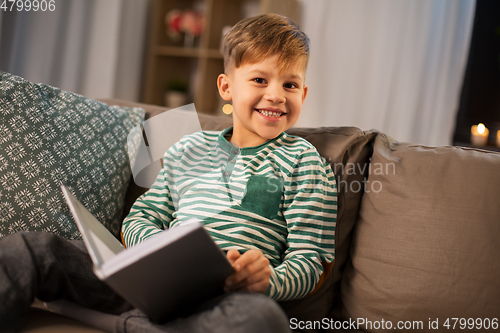 Image of happy smiling little boy reading book at home