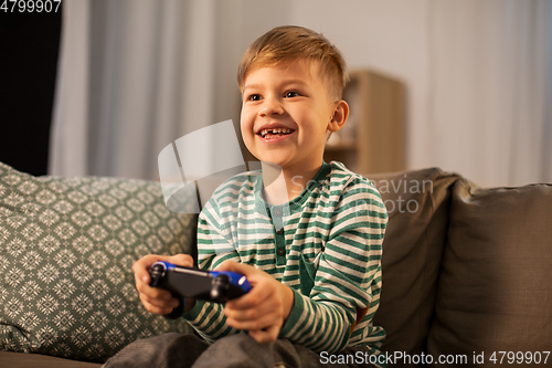 Image of little boy with gamepad playing video game at home