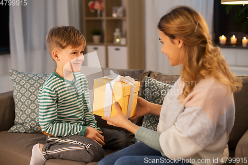 Image of mother giving present to her little son at home