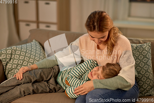 Image of happy mother with sleeping little son at home