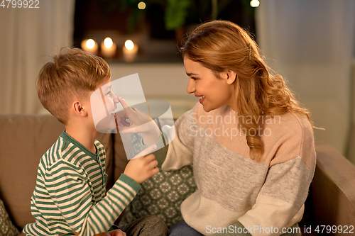 Image of happy mother touching little son's nose at home