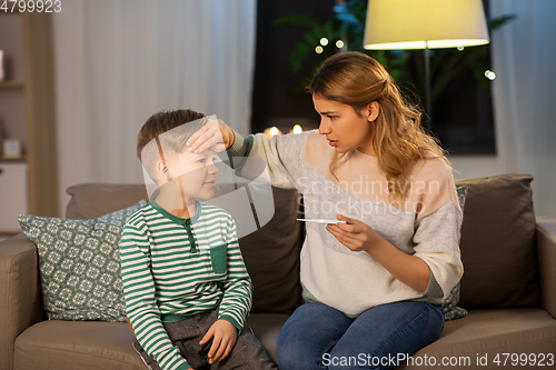 Image of sad mother with thermometer and ill son at home