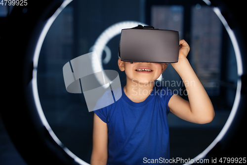 Image of boy in vr glasses over illumination in dark room