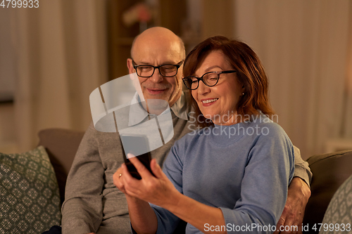 Image of happy senior couple with smartphone at home