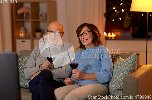 Image of happy senior couple drink red wine and watch tv