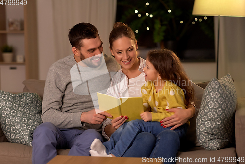 Image of happy family reading book at home at night