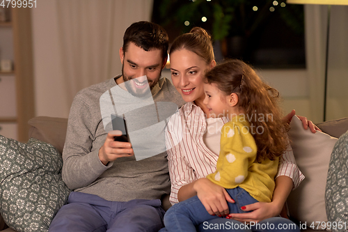 Image of happy family with smartphone at home at night