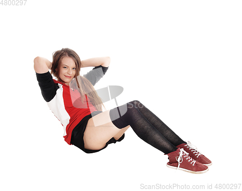 Image of Young woman doing sit-ups on the floor