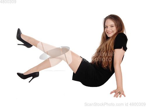 Image of Young woman sitting on floor, legs up