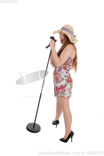 Image of Woman standing and singing with straw hat