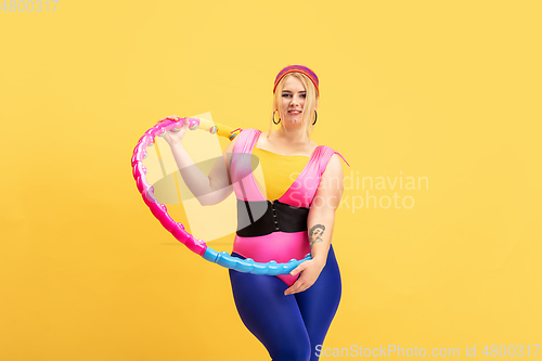Image of Young caucasian plus size female model\'s training on yellow background