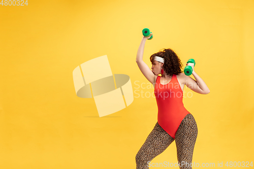 Image of Young caucasian plus size female model\'s training on yellow background
